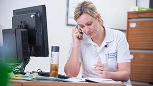 a physio making notes while on the phone